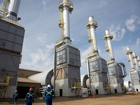 Des employés marchent devant des générateurs de vapeur au gaz naturel à l'installation de sables bitumineux Cenovus SAGD, près de Conklin, en Alberta.