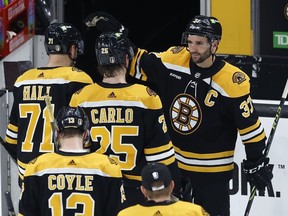 Patrice Bergeron (en haut à droite) des Bruins de Boston salue ses coéquipiers alors qu'ils quittent la glace après avoir perdu contre les Panthers de la Floride en prolongation lors du match 7 d'une série éliminatoire de premier tour de la Coupe Stanley de hockey de la LNH, le dimanche 30 avril 2023, à Boston.