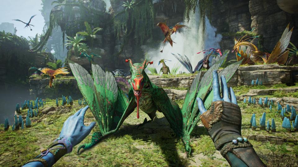 Deux mains bleues sont représentées à la première personne.  Ils semblent essayer de calmer une créature ressemblant à un dragon dans Avatar : Frontiers of Pandora.