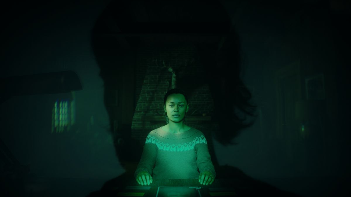 A woman surrounded by green light sits at a table with Alan Wake