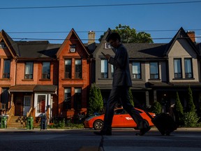 Un piéton passe devant des maisons à Toronto.