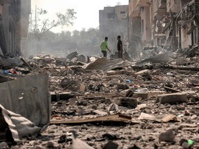 Des hommes se tiennent au milieu des débris et des destructions qui jonchent une rue du camp de réfugiés palestiniens de Jabalia, dans la ville de Gaza, le 11 octobre 2023, au cinquième jour des combats entre le mouvement islamiste palestinien Hamas et Israël.