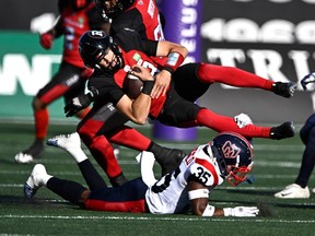 Le quart-arrière des Rouge et Noir Dustin Crum est plaqué par Reggie Stubblefield des Alouettes en première mi-temps.