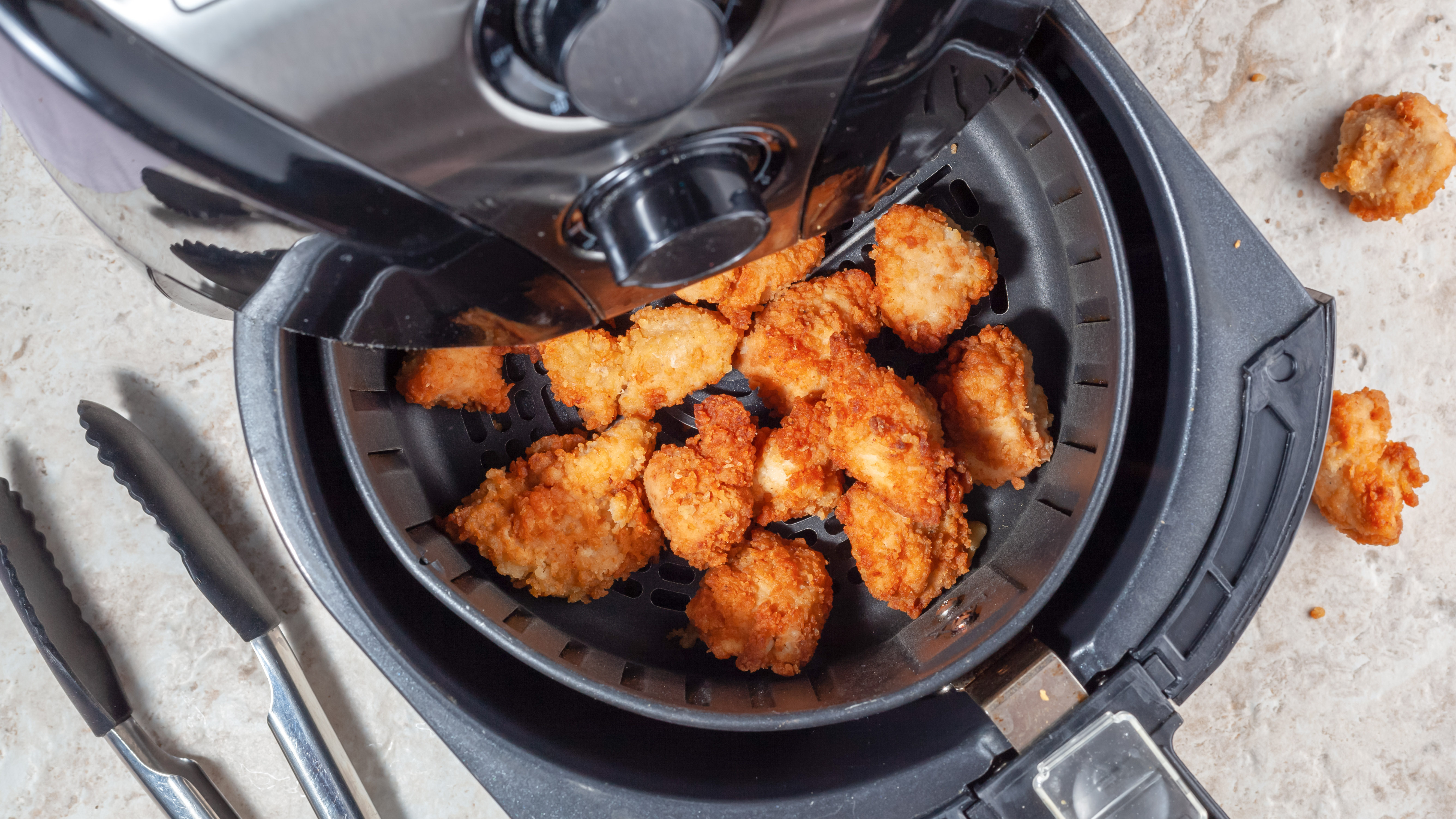 Friteuse à air avec du papier d'aluminium placé pour le poulet