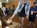 Un homme, à droite, attend qu'une femme dépose son bulletin de vote dans une urne dans un bureau de vote à Redfern alors que les Australiens votent pour la dernière fois à Sydney, le samedi 14 octobre 2023, lors de leur premier référendum d'une génération qui vise à lutter contre les désavantages autochtones. en inscrivant dans la constitution un nouveau comité de plaidoyer.  Les électeurs ont catégoriquement rejeté la proposition.