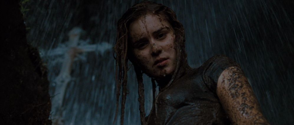 Alison Lohman dans le rôle de Christine Brown debout dans une tombe ouverte avec une croix visible en arrière-plan, trempée de boue et d'eau de pluie dans Drag Me to Hell.