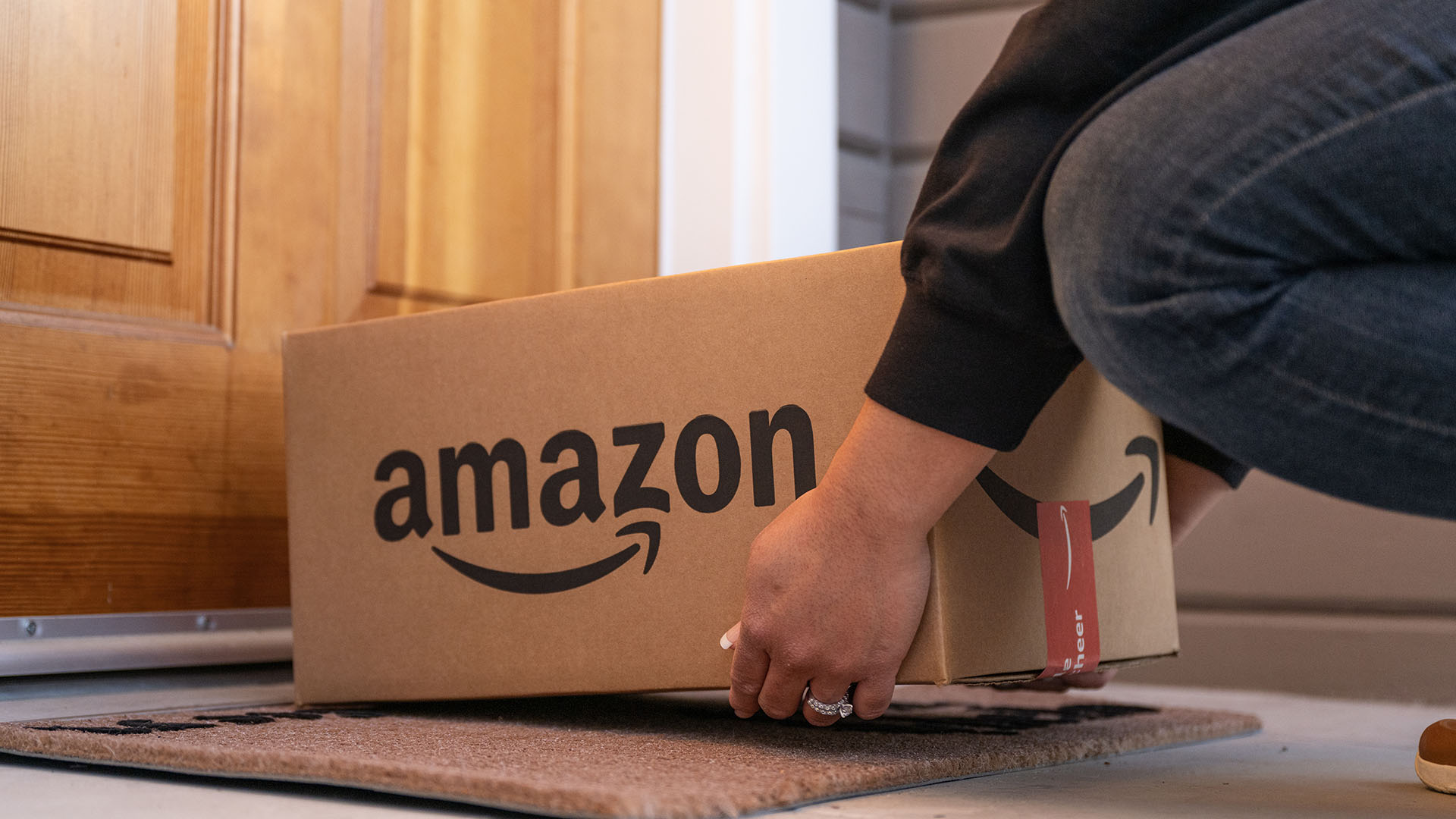 Personne plaçant une boîte Amazon devant une porte