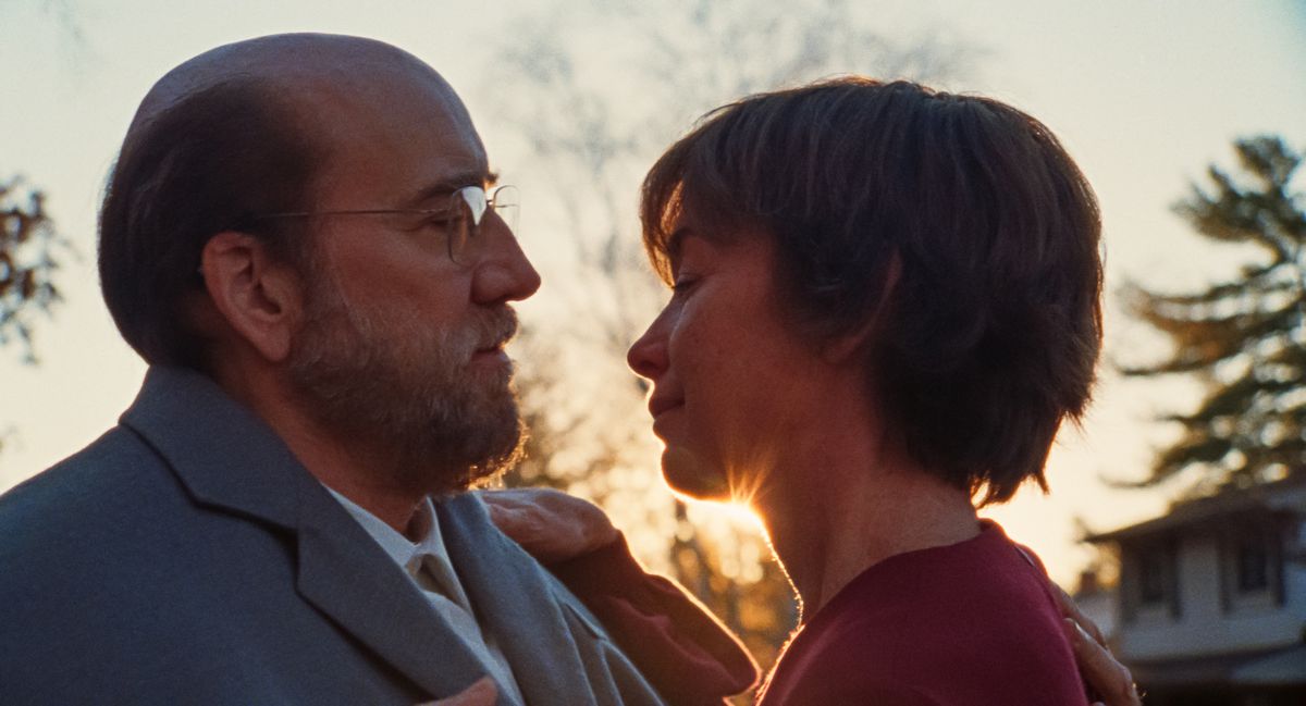 Le professeur chauve Paul Matthews (Nicolas Cage) et sa femme Janet (Julianne Nicholson) se penchent l'un vers l'autre en gros plan avec le soleil offrant un point culminant derrière eux dans le film Dream Scenario d'A24.