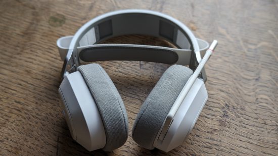 Test du Corsair HS80 Max : un casque blanc avec microphone rétractable apparaît sur une table en bois.