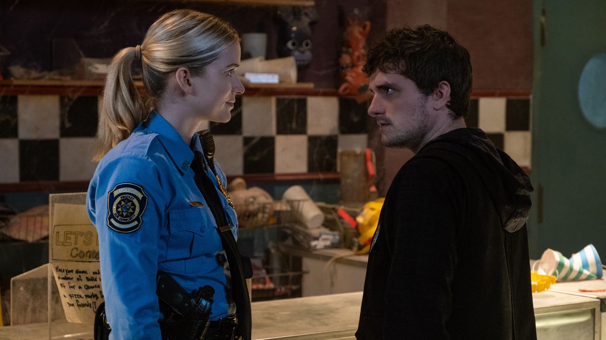 Mike (Josh Hutcherson), agent de sécurité de nuit, meurtri et aux yeux fous, affronte la flic à l'air joyeux Vanessa (Elizabeth Lali) dans le film Five Nights at Freddy's.