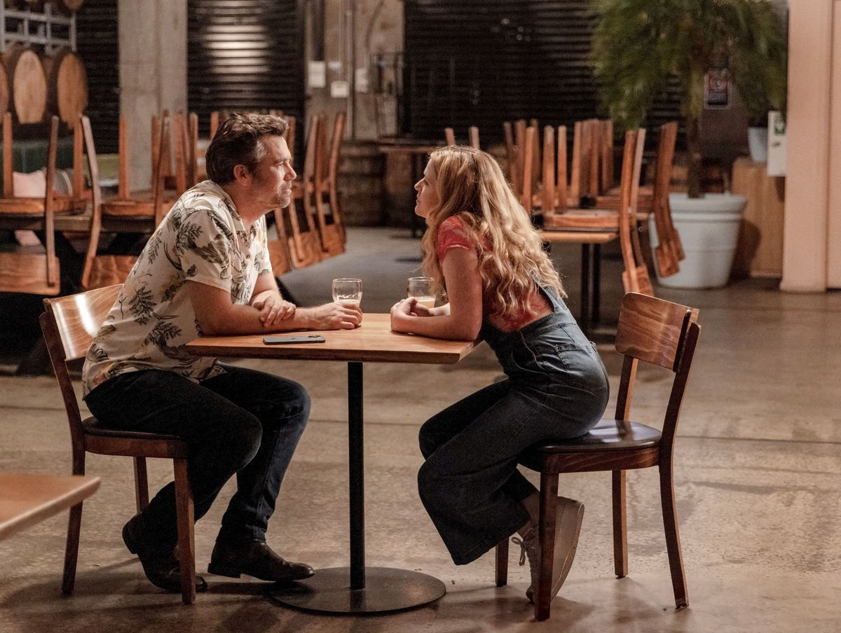 Gordon et Ashley se penchent l'un vers l'autre au-dessus d'une table dans une brasserie déserte dans Colin From Accounts