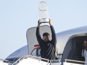 Marcus Semien des Texas Rangers hisse le Trophée du commissaire à côté du lanceur José Leclerc à l'arrivée de l'équipe de baseball au Dallas Love Field le jeudi 2 novembre 2023, à Dallas, le lendemain de leur victoire en Série mondiale contre les Diamondbacks de l'Arizona.