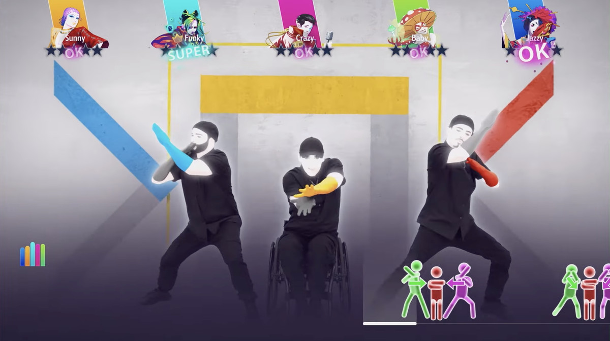 Une image de trois personnages de Just Dance.  Celui du milieu danse assis dans un fauteuil roulant.  Il tend les mains et les tord au rythme de la chanson.