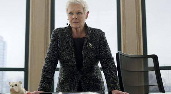 Dame Judi Dench standing at her desk, with Jack the Bulldog in Skyfall.