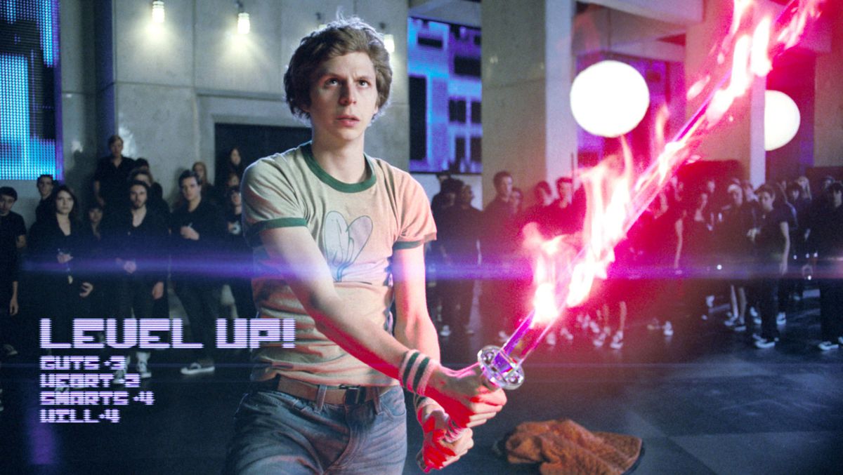 Michael Cera dans le rôle de Scott dans Scott Pilgrim contre le monde.  Il brandit un katana entouré de flammes roses, des lettres numériques sur le côté de l'écran proclament LEVEL UP !