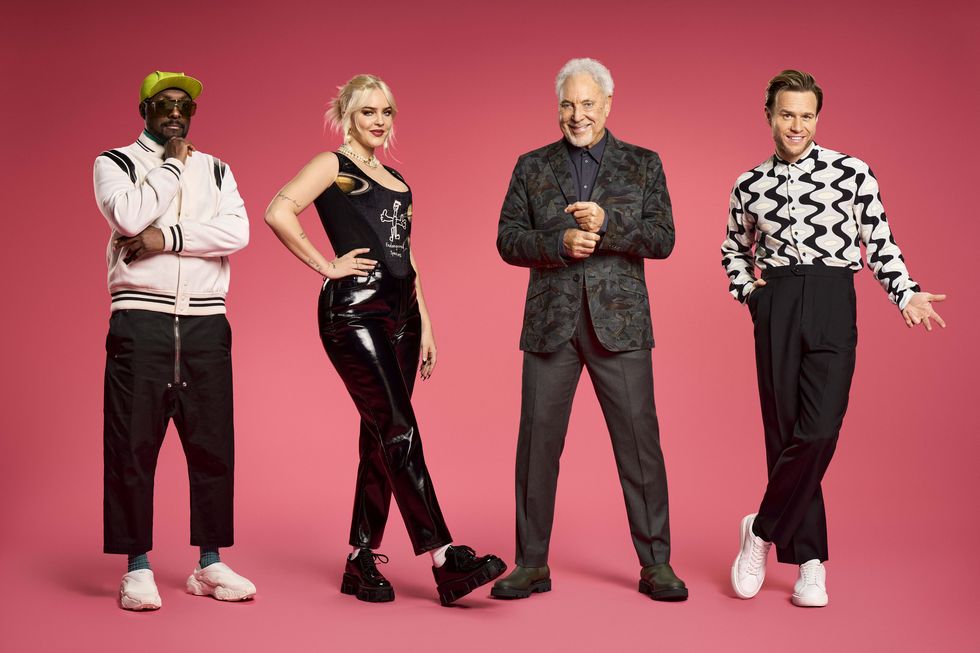 les entraîneurs Voice UK, will i am, anne marie, sir tom jones et olly murs, se tiennent alignés posant pour la caméra devant un fond rose