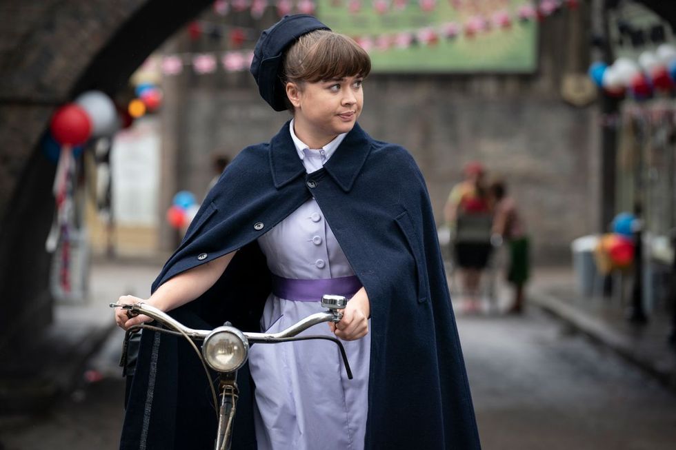 appelle la sage-femme Nancy Corrigan dans son uniforme marchant avec son vélo