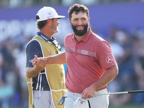 L'Espagnol Jon Rahm serre la main de son caddie, Adam Hayes (masqué), sur le 18e green lors du quatrième jour du championnat DP World Tour sur le Earth Course du Jumeirah Golf Estates le 19 novembre 2023 à Dubaï, aux Émirats arabes unis.