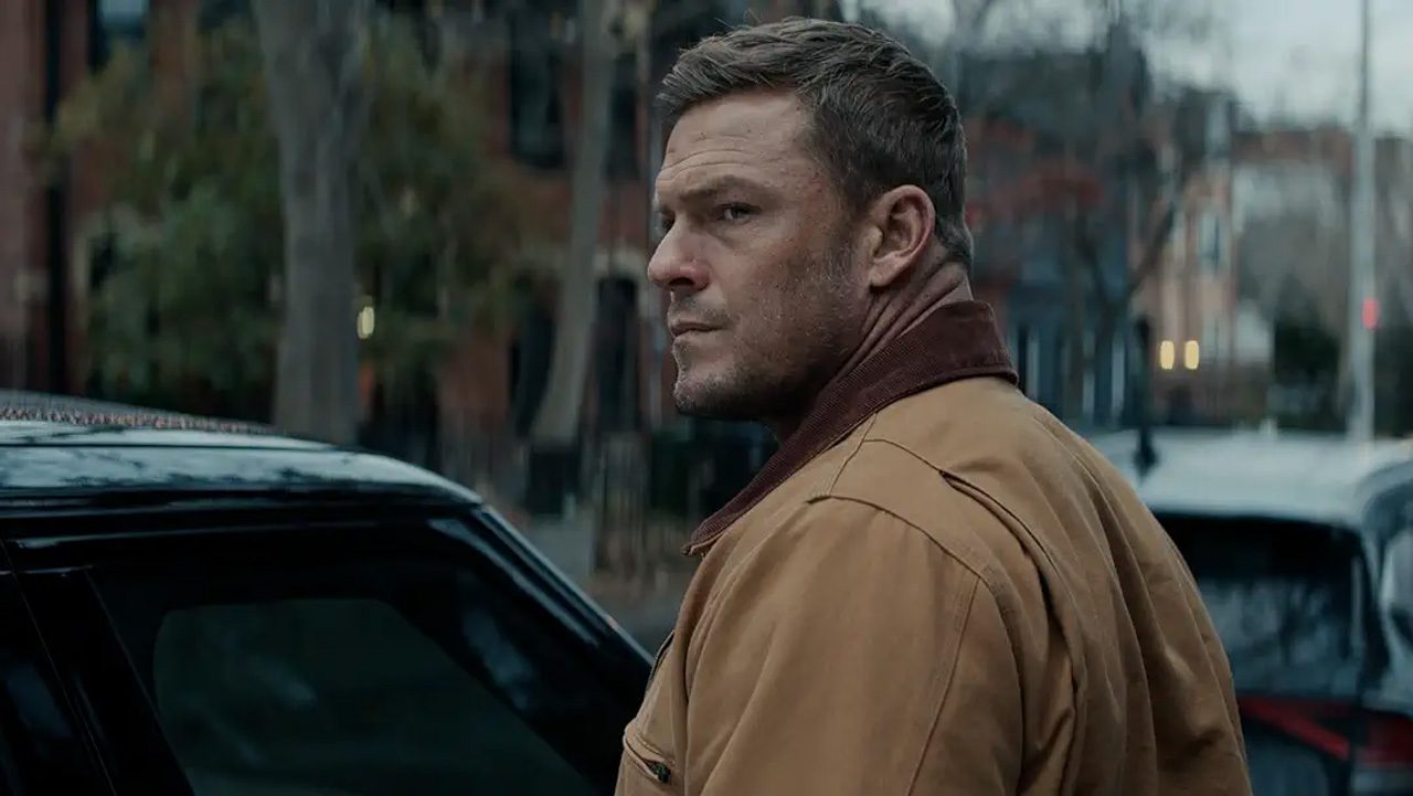 A stocky man, Jack Reacher, standing by a car.