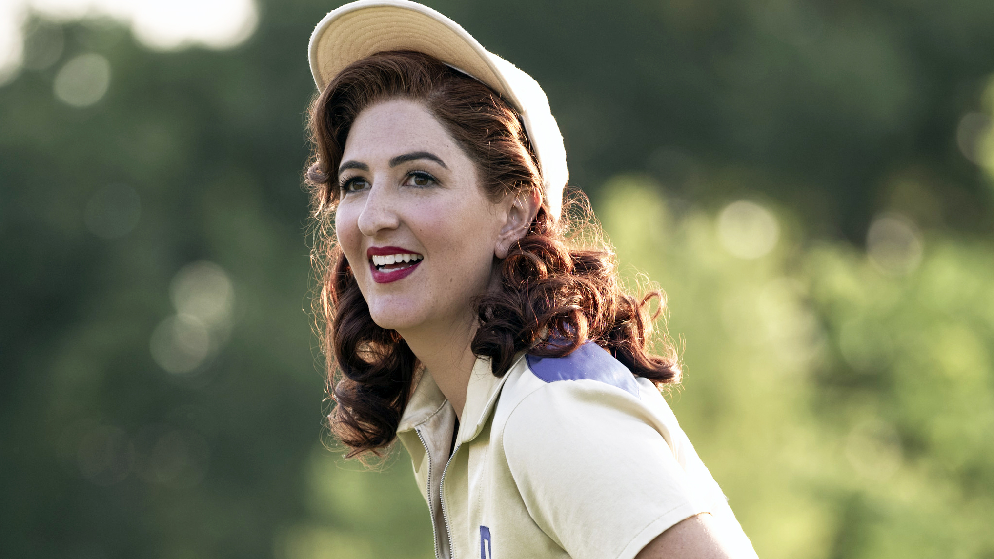 D'Arcy Carden (Greta) sourit sur le terrain dans A League of Their Own