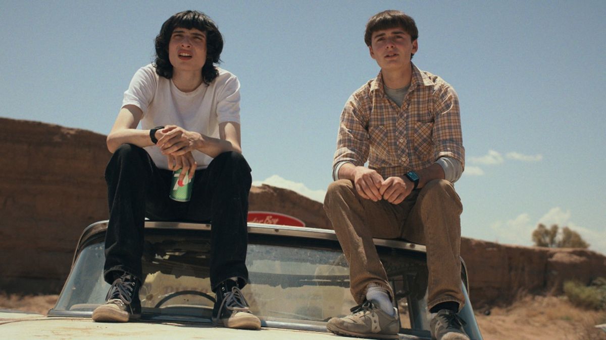 Mike and Will sitting on top of a car on Stranger Things looking into the distance.