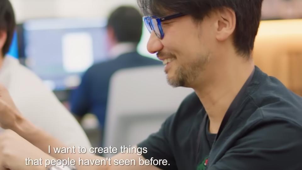 Extrait de la bande-annonce du documentaire Hideo Kojima : Connecting Worlds.  Le concepteur du jeu est assis, souriant, dans un environnement de travail.  Une légende dit, 