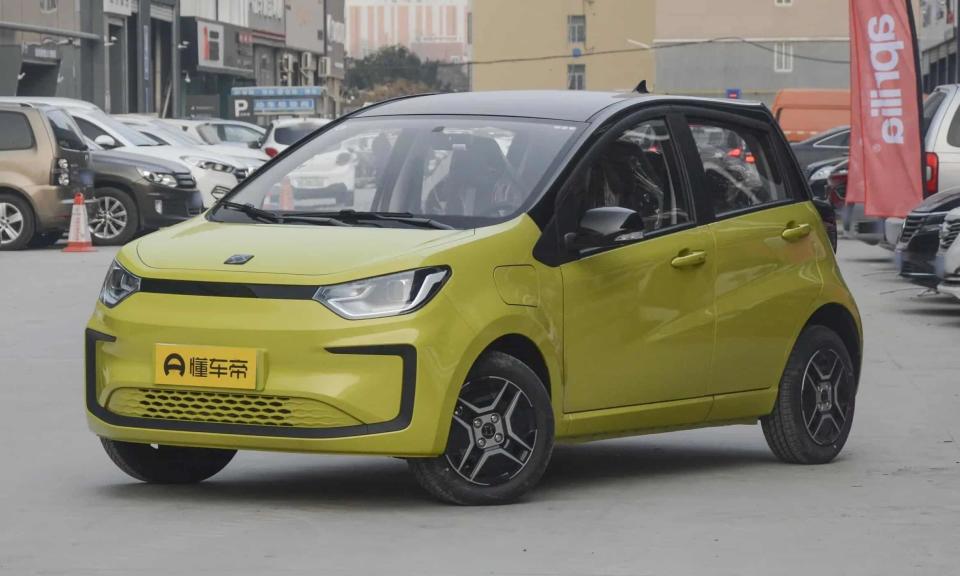 Le Sehol E10X, dévoilé plus tôt cette année.  La berline jaune se trouve dans un parking urbain avec des voitures garées et des bâtiments derrière elle.