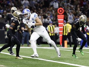 L'ailier rapproché des Detroit Lions Sam LaPorta (87), défendu par le cornerback des New Orleans Saints Alontae Taylor (1) et la sécurité Jordan Howden (31), court pour un touché le dimanche 3 décembre 2023, à la Nouvelle-Orléans.