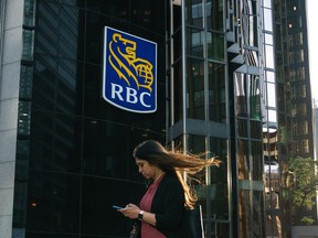 Une femme passe devant une pancarte de la Banque Royale du Canada dans le quartier financier de Toronto.