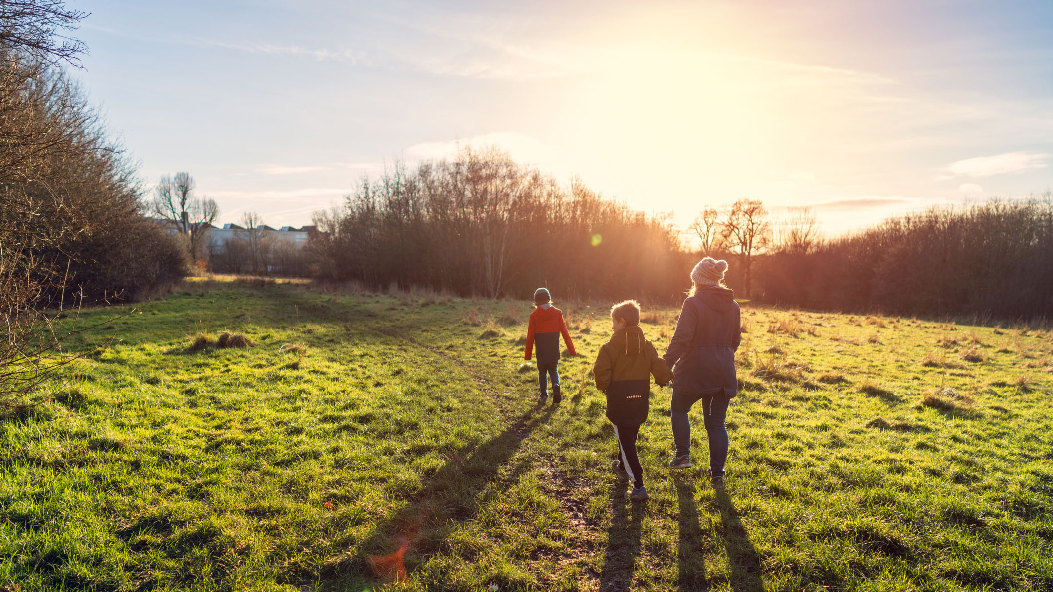 Une femme et ses deux enfants se promènent tôt le matin sous le soleil d'hiver