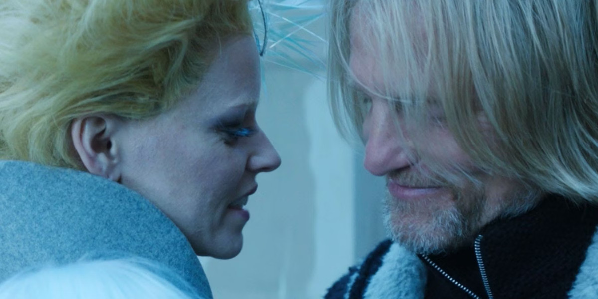 Haymitch Abernathy et Effie Trinket de The Hunger Games sont assis l'un près de l'autre.  Leurs visages sont si proches qu’ils pourraient s’embrasser !