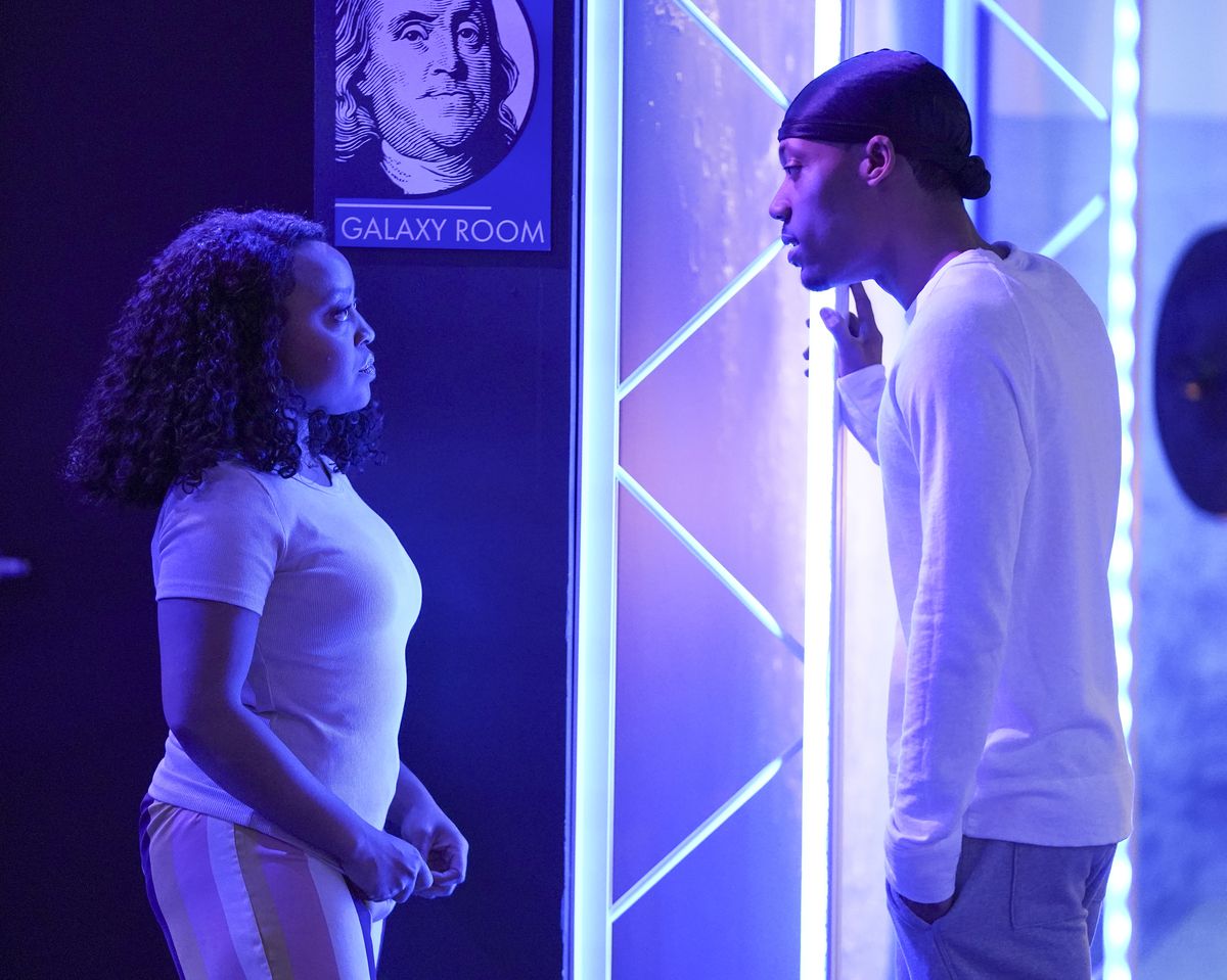 Janine et Gregory se tiennent devant un bar de l'école primaire Abbott.  Ils se regardent profondément dans les yeux pendant qu’ils se parlent. 