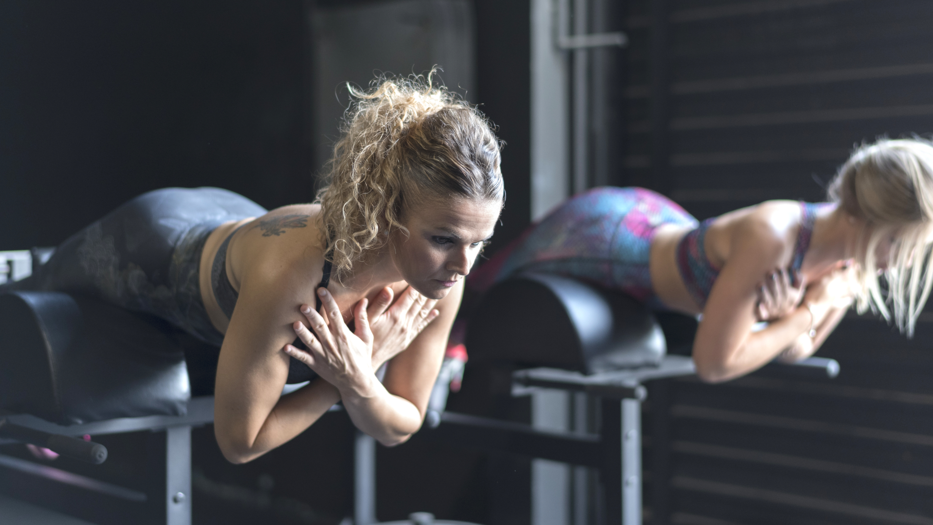 une photo de deux femmes effectuant des extensions de dossier de chaise romaine