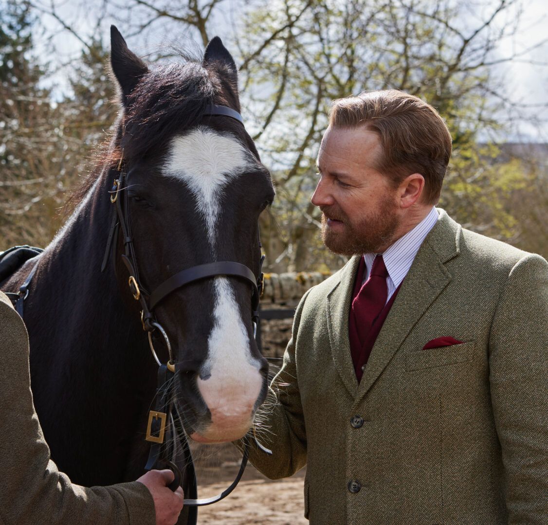 Siegfried porte un costume en laine et regarde un cheval avec adoration dans Toutes les créatures, grandes et petites.