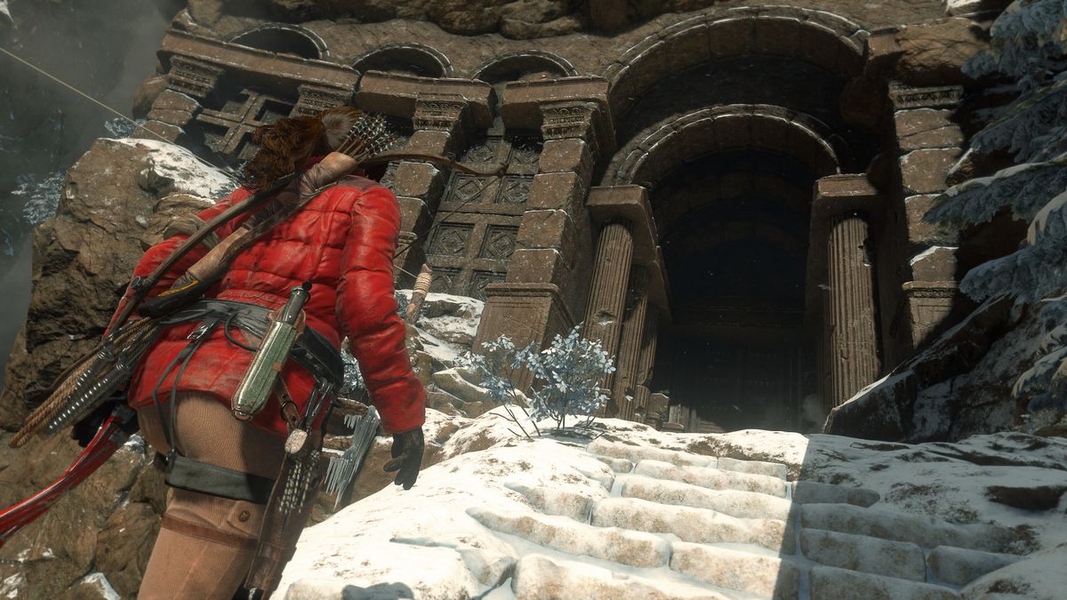 Lara Croft dans une veste d'hiver rouge gravissant les marches enneigées d'un temple dans Rise of the Tomb Raider.