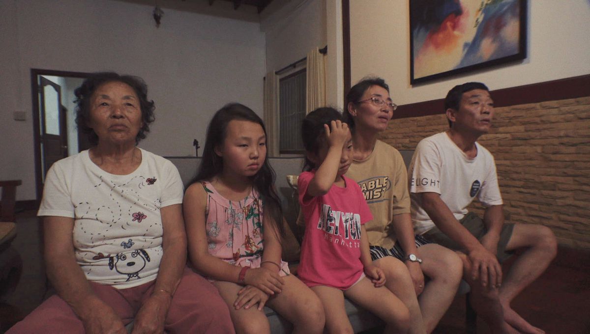 La famille Roh assise sur un canapé, regardant hors écran dans Beyond Utopia.