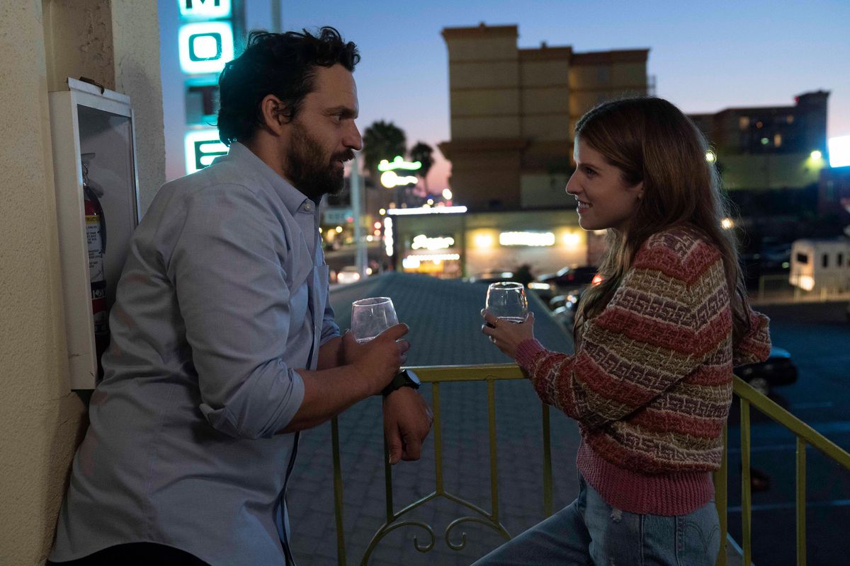 (De gauche à droite) Jake Johnson et Anna Kendrick debout sur un balcon, buvant dans des verres sans pied dans Self Reliance.