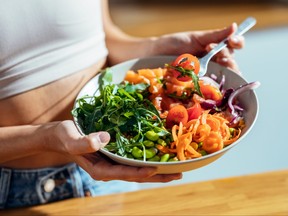 Femme de remise en forme mangeant un bol de poke sain dans la cuisine à la maison.