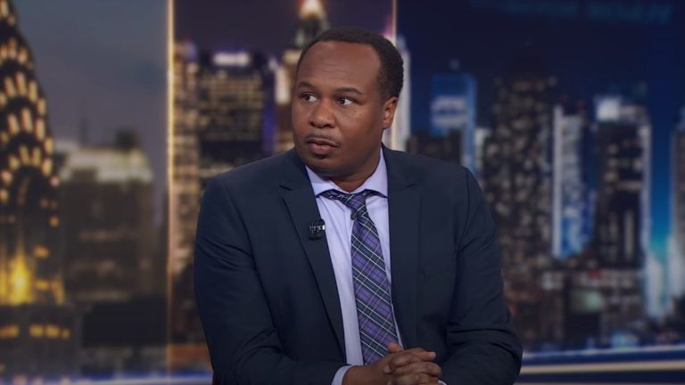 Roy Wood Jr. sitting at the main desk on The Daily Show.