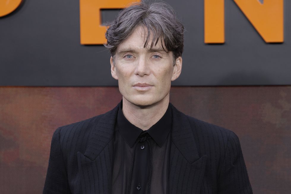 Cillian Murphy pose pour la caméra dans un costume noir et une chemise noire