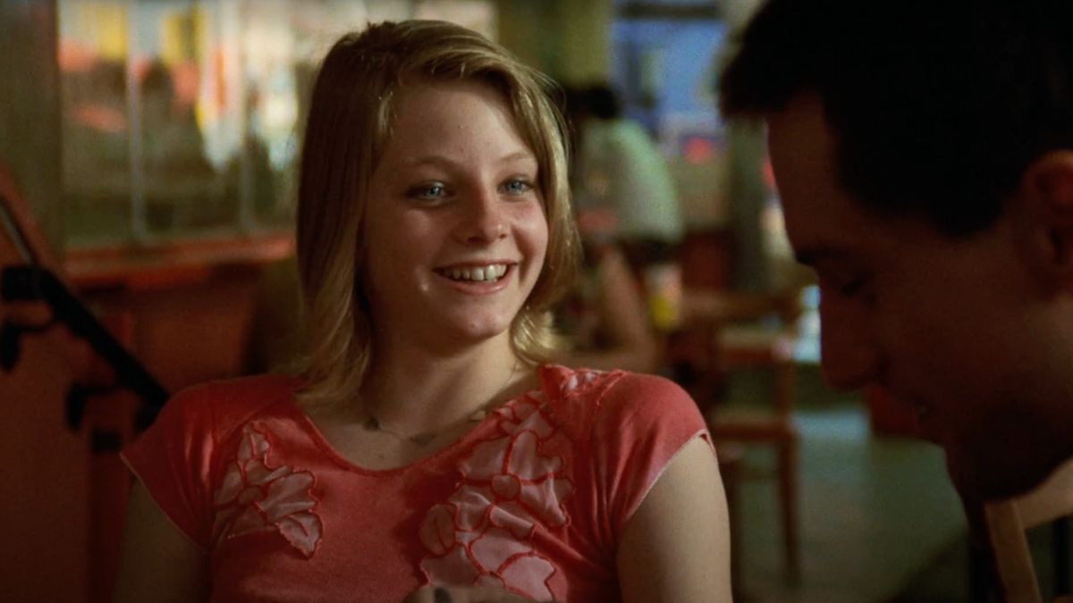 Jodie Foster laughs while talking at the table in Taxi Driver.