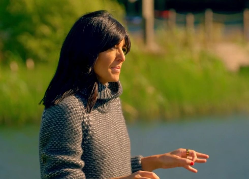 Claudia Winkleman à propos de l'épisode 4 de la série 2 des traîtres, faisant des gestes à l'extérieur dans un col roulé gris en grosse maille