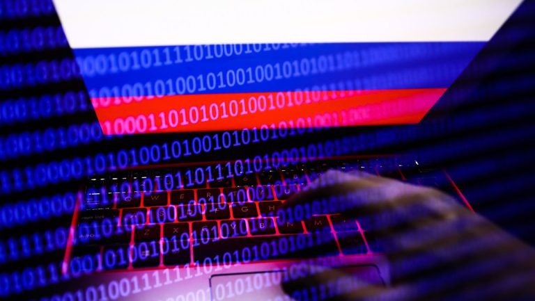 Russian flag displayed on a laptop screen and binary code code displayed on a screen are seen in this multiple exposure illustration photo taken in Krakow, Poland on February 16, 2022. (Photo illustration by Jakub Porzycki/NurPhoto via Getty Images)