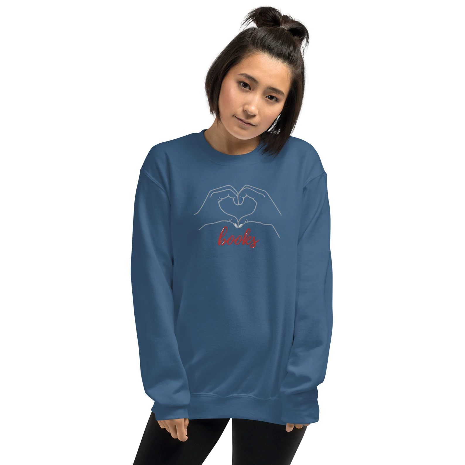 Image d’une femme à la peau olive portant un sweat-shirt bleu.  Le sweat-shirt a une broderie blanche d'un cœur réalisé à deux mains avec le mot "livres" ci-dessous. 