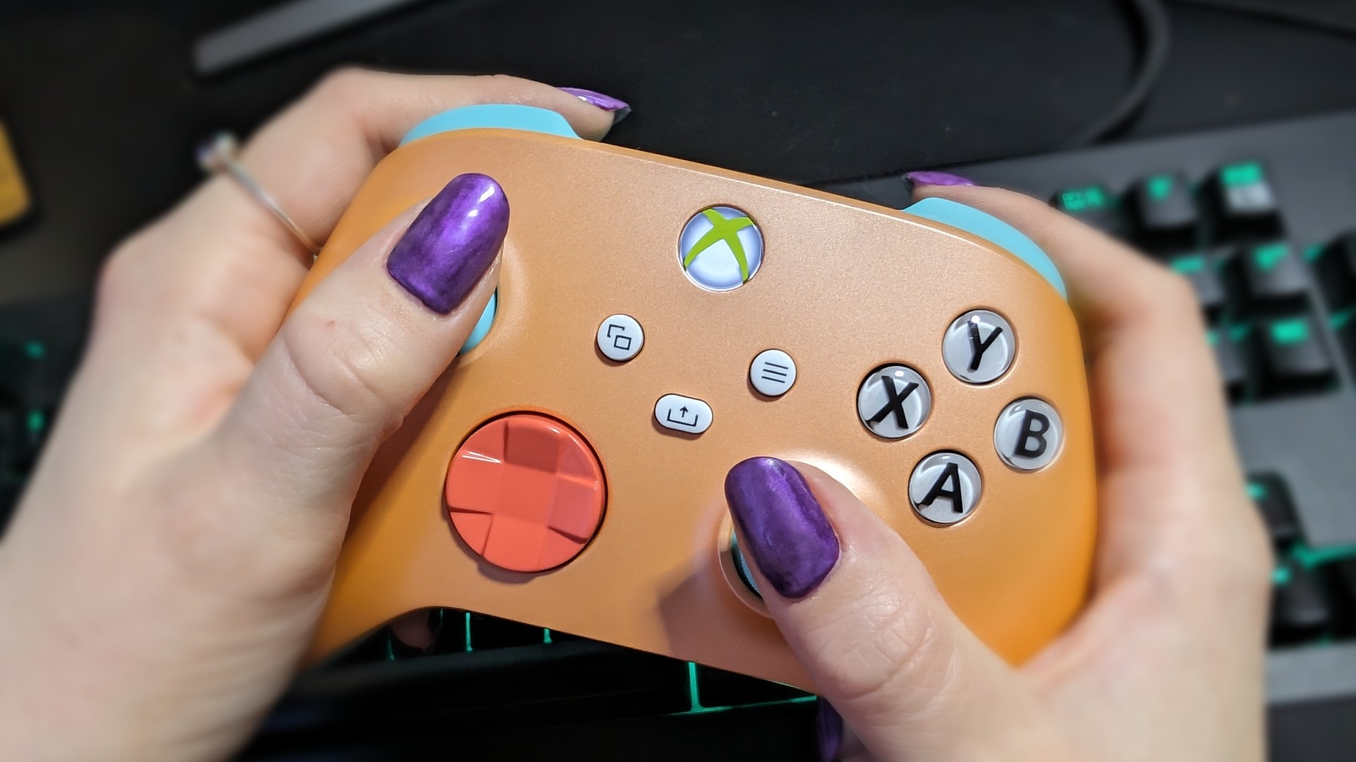 Image d'examen de la manette sans fil Xbox montrant deux mains humaines tenant la manette au-dessus d'un clavier.