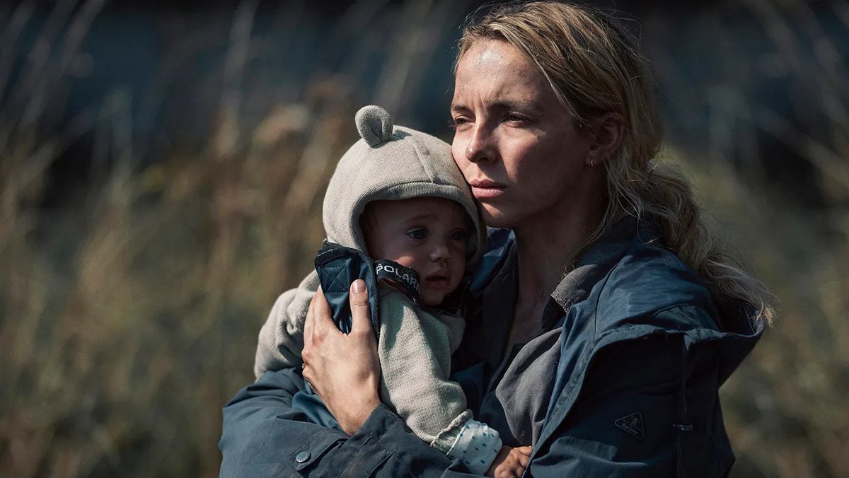 Une femme tenant dans ses bras un enfant portant un sweat à capuche sur le thème de l'ours.