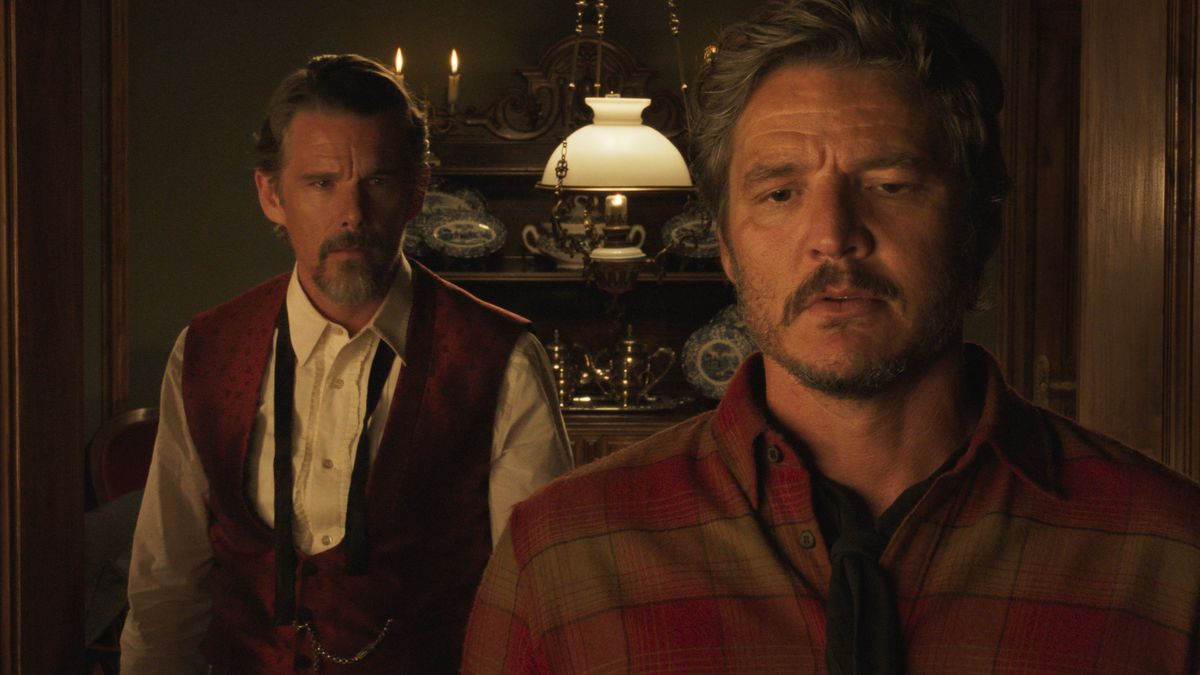 Deux hommes (Ethan Hawke, Pedro Pascal) debout dans une salle à manger faiblement éclairée dans Strange Way of LIfe.