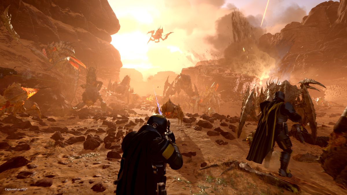 Une escouade de Helldivers dans Helldivers 2 combat une armée d'insectes sur une planète désertique