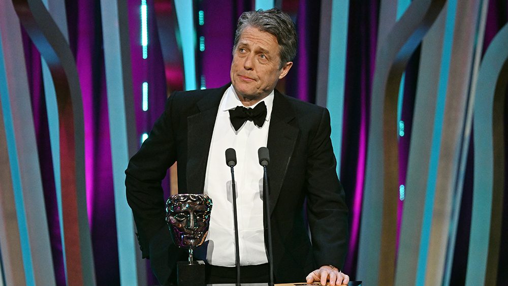 LONDON, ENGLAND - FEBRUARY 18: Hugh Grant presents the Director Award on stage during the EE BAFTA Film Awards 2024 at The Royal Festival Hall on February 18, 2024 in London, England. (Photo by Kate Green/BAFTA/Getty Images for BAFTA)