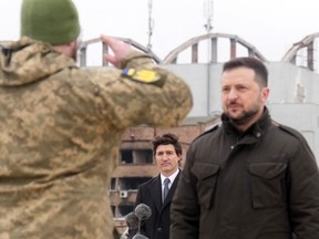 Le premier ministre Justin Trudeau regarde le président ukrainien Volodymyr Zelenskyy être salué par des soldats lors d'une cérémonie à l'aéroport Hostomel de Kiev, le samedi 24 février 2024. La cérémonie faisait partie d'une journée de commémorations marquant le deuxième anniversaire du début de la guerre. en Ukraine.